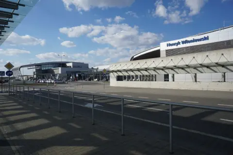 Nowoczesny budynek portu lotniczego im. Henryka Wieniawskiego, z charakterystycznym zadaszeniem i parkingiem.