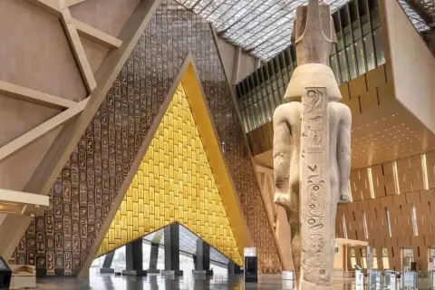 Wielki posąg faraona w nowoczesnym muzeum egipskim. Ściany zdobią hieroglify i złote panele.