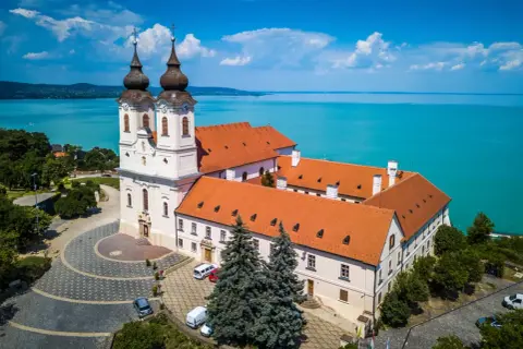 Opactwo na Półwyspie Tihany, gdzie nad Balatonem rozpościera się błękitne niebo i turkusowa woda.