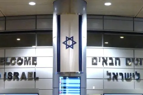 Powitanie "Welcome to Israel" i hebrajskie napisy. Flaga Izraela zwisa z kolumny. Wiza do Izraela jest ważna.