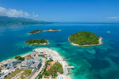 Rajska plaża Ksamil z turkusową wodą i zielonymi wysepkami. Idealne miejsce na wakacje.