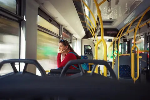 Kobieta w czerwonej bluzce podróżuje autobusem, zastanawiając się, czy Bułgaria jest bezpieczna.