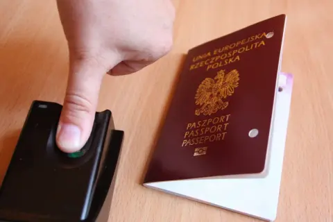 Palec na czytniku linii papilarnych obok polskiego paszportu. To pokazuje, ile ważny jest paszport w podróży.