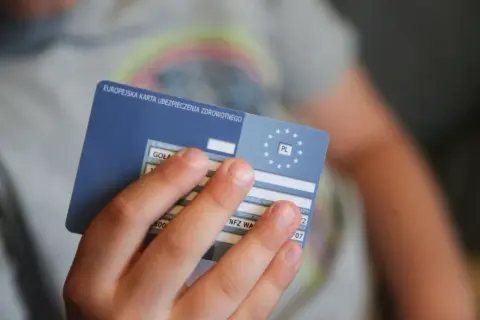 Dziecko trzyma Europejską Kartę Ubezpieczenia Zdrowotnego, niezbędną do podróży, np. na Słowację.