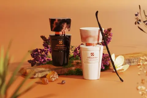 Dwa eleganckie flakony perfum Olfazeta, czarny i biały, otoczone kwiatami i laską wanilii. Idealne kosmetyki w bagażu rejestrowanym na podróż.