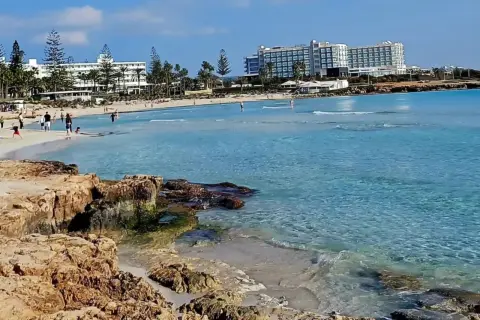 Słoneczny dzień na plaży Ayia Napa. Turkusowa woda, piaszczysty brzeg i hotele w tle.