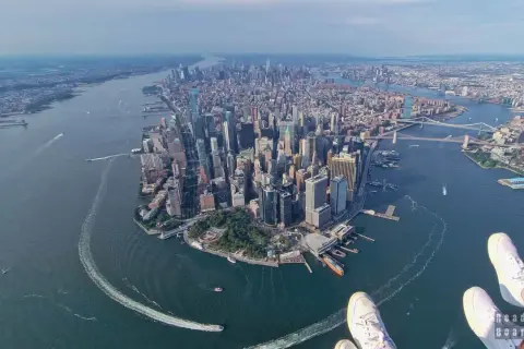 Widok z lotu ptaka na Manhattan, pełen drapaczy chmur, rzekę i mosty. Widać, w jakim stanie jest Nowy Jork – tętniący życiem, dynamiczny.