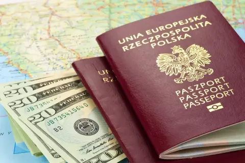 Dwa polskie paszporty i stos banknotów dolarowych na tle mapy. Czy do Rumunii potrzebny jest paszport? Tak, jeśli nie jesteś obywatelem UE.