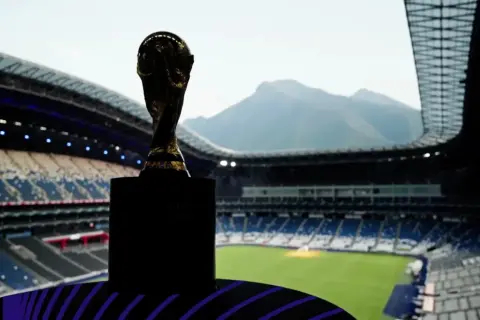 Złoty puchar mistrzostw świata na tle trybun stadionu, który mógłby być największym stadionem na świecie.