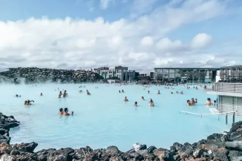 Relaks w Blue Lagoon, geotermalnym spa na Islandii. Ludzie kąpią się w mlecznoniebieskiej wodzie, otoczeni wulkanicznymi skałami i nowoczesną architekturą.