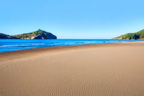 Piękna plaża w Sarigerme, z piaszczystym brzegiem i turkusowym morzem, w tle skaliste wzgórza.