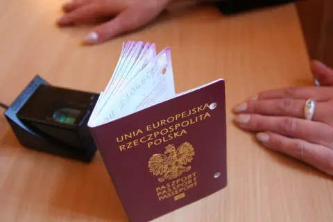 Polski paszport obok skanera linii papilarnych. Dokument z godłem Polski, gotowy do podróży.