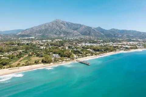 Widok na marbella beach z turkusową wodą, piaszczystą plażą i górami w tle.