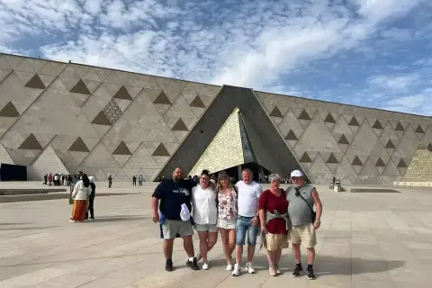 Rodzina pozuje przed nowoczesnym muzeum w Gizie, którego fasada ozdobiona jest geometrycznymi wzorami.