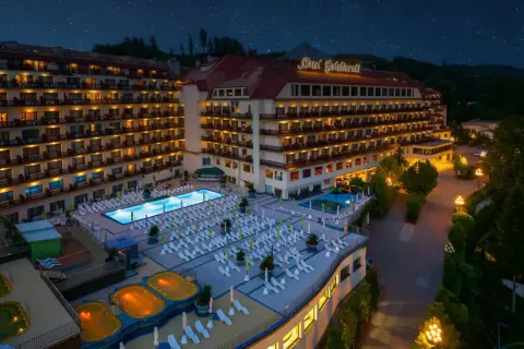 Hotel Gołębiewski Wisła nocą, z podświetlonym basenem, jacuzzi i licznymi leżakami.