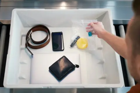 Kuba przygotowuje się do lotów, wykładając rzeczy do kontroli bezpieczeństwa: pasek, telefon, portfel, laptop i kosmetyczkę.
