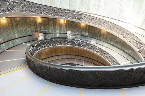 Watykańska, spiralna klatka schodowa z bogatymi zdobieniami, gdzie ludzie spieszą na audiencję u papieża.