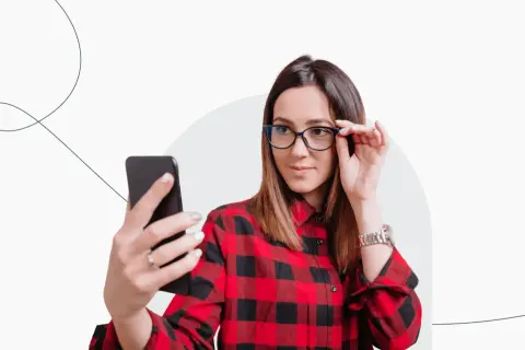 Kobieta w okularach i koszuli w kratę robi selfie, zastanawiając się, czy do Finlandii potrzebny jest paszport.