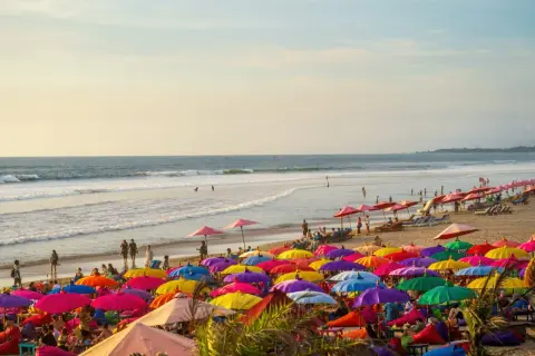 Kolorowa plaża na Bali, pełna parasoli i ludzi relaksujących się na leżakach. Idealne miejsce na wakacje.
