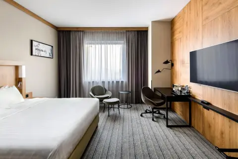 Nowoczesny pokój w jednym z **courtyard hotels Warsaw**. Duże łóżko, wygodne fotele i biurko przy oknie.
