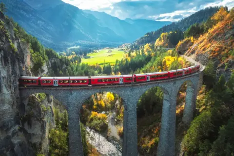 Czerwony pociąg Bernina Express przemierza malowniczy alpejski krajobraz jesienią. Sprawdź bernina express cena i zaplanuj podróż!