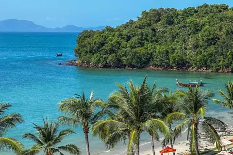 Rajska plaża Ao Nang z palmami, turkusową wodą i łodziami.