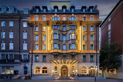 Elegancki hotel w Londynie z oświetloną fasadą i wejściem.