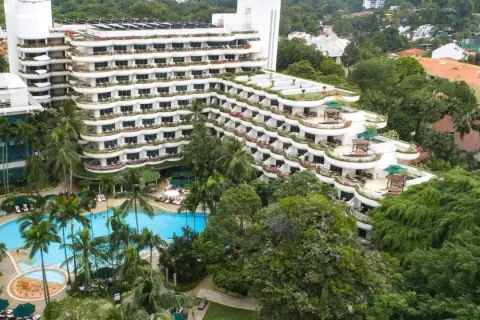 Luksusowy hotel z basenem i palmami, otoczony bujną zielenią, przypomina tropikalny raj, prawdziwe shangri la.
