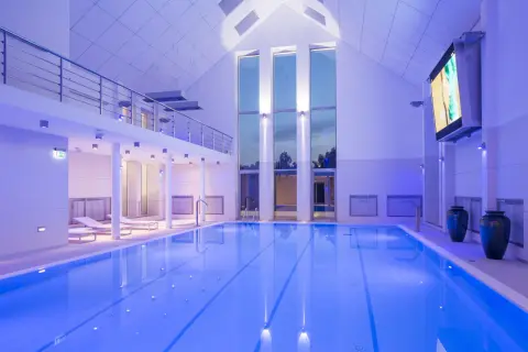Basen w narie resort & spa, oświetlony niebieskim światłem, z leżakami i dużymi oknami.
