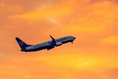 Samolot Ryanair wznosi się na tle pomarańczowego nieba. Idealny na krótkie wycieczki 4 dniowe samolotem.
