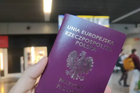 Polski paszport w dłoni, gotowy do podróży. Może to być początek drogi po wizę do Anglii.