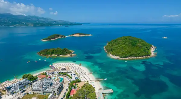 Rajska plaża Ksamil z turkusową wodą i zielonymi wysepkami. Idealne miejsce na wakacje.