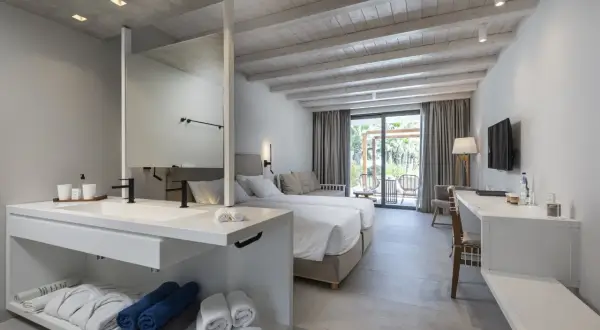 Pokój hotelowy z dwoma łóżkami, łazienką i widokiem na taras, idealny na pobyt w Caravia Beach Kos.