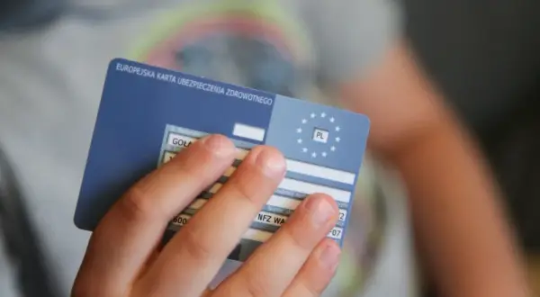 Dziecko trzyma Europejską Kartę Ubezpieczenia Zdrowotnego, niezbędną do podróży, np. na Słowację.