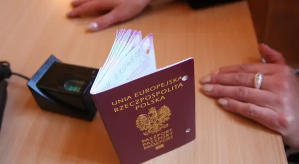 Polski paszport obok skanera linii papilarnych. Dokument z godłem Polski, gotowy do podróży.