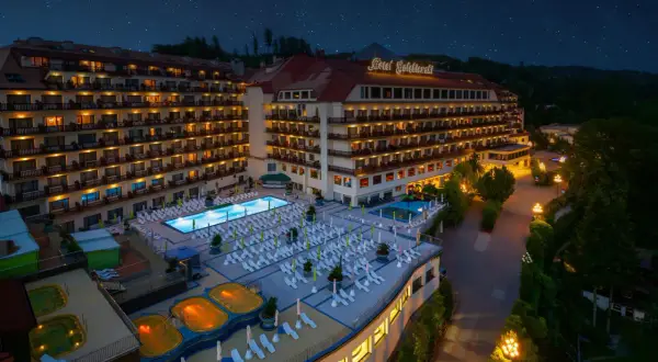 Hotel Gołębiewski Wisła nocą, z podświetlonym basenem, jacuzzi i licznymi leżakami.