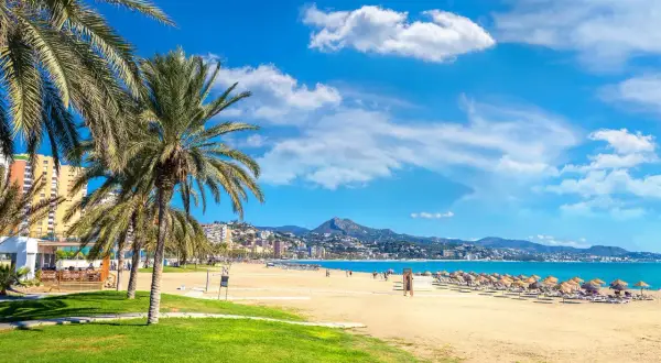 Malaga plaże: palmy, złoty piasek, turkusowe morze i góry w tle. Idealne miejsce na relaks.
