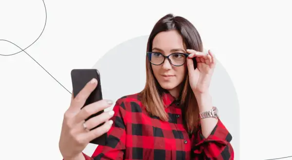 Kobieta w okularach i koszuli w kratę robi selfie, zastanawiając się, czy do Finlandii potrzebny jest paszport.