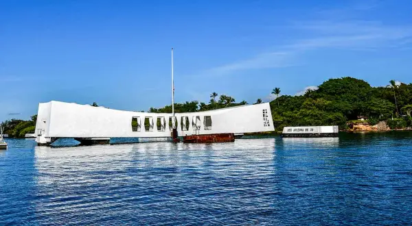 Pomnik USS Arizona w Pearl Harbor, biała konstrukcja nad wodą, upamiętnia tragiczne wydarzenia.