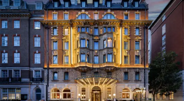 Elegancki hotel w Londynie z oświetloną fasadą i wejściem.