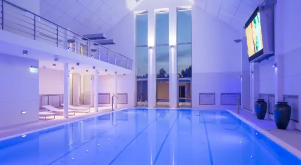 Basen w narie resort & spa, oświetlony niebieskim światłem, z leżakami i dużymi oknami.