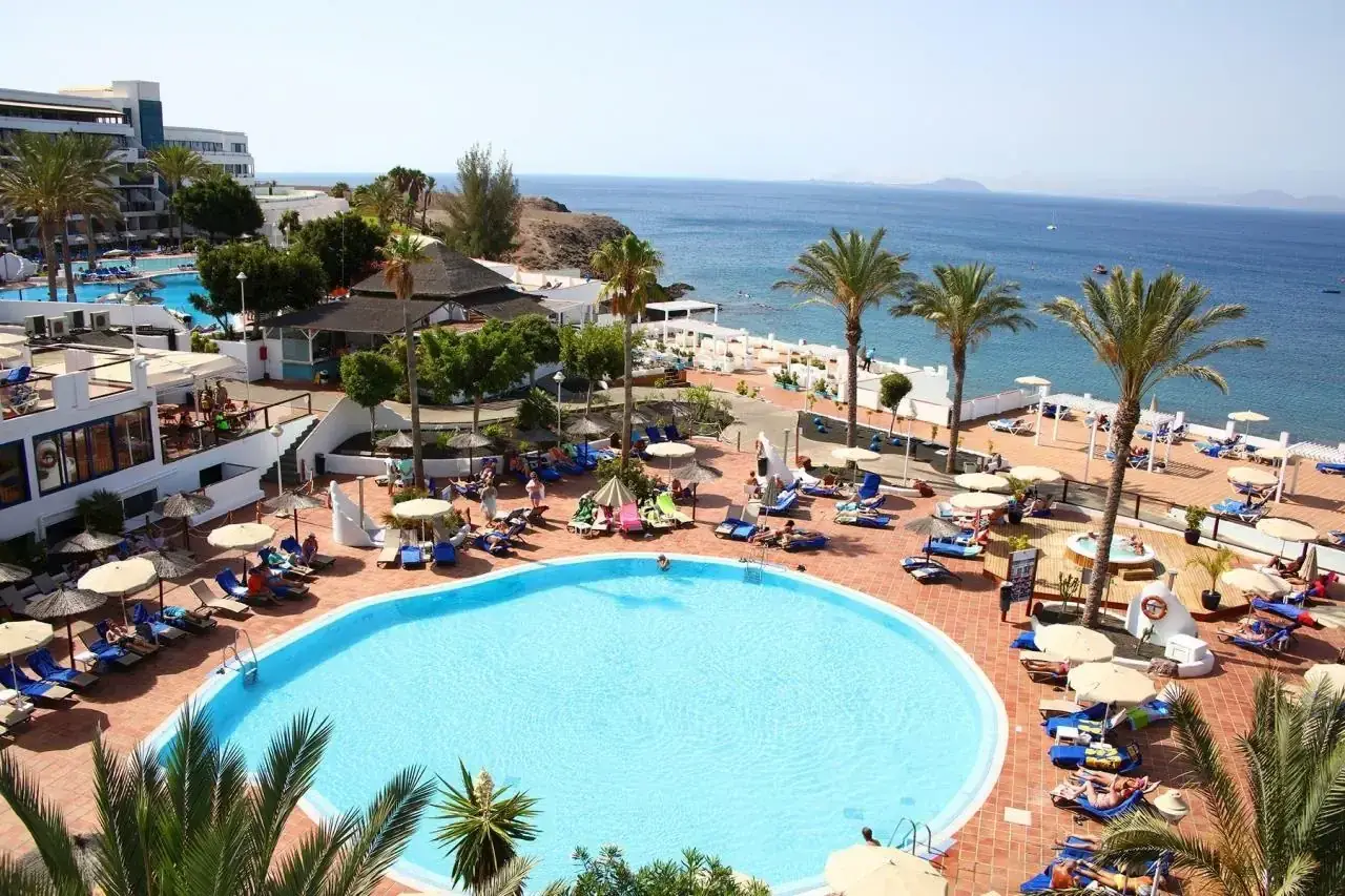 Relaks na basenie w hotelu Sandos, z widokiem na morze i palmami.
