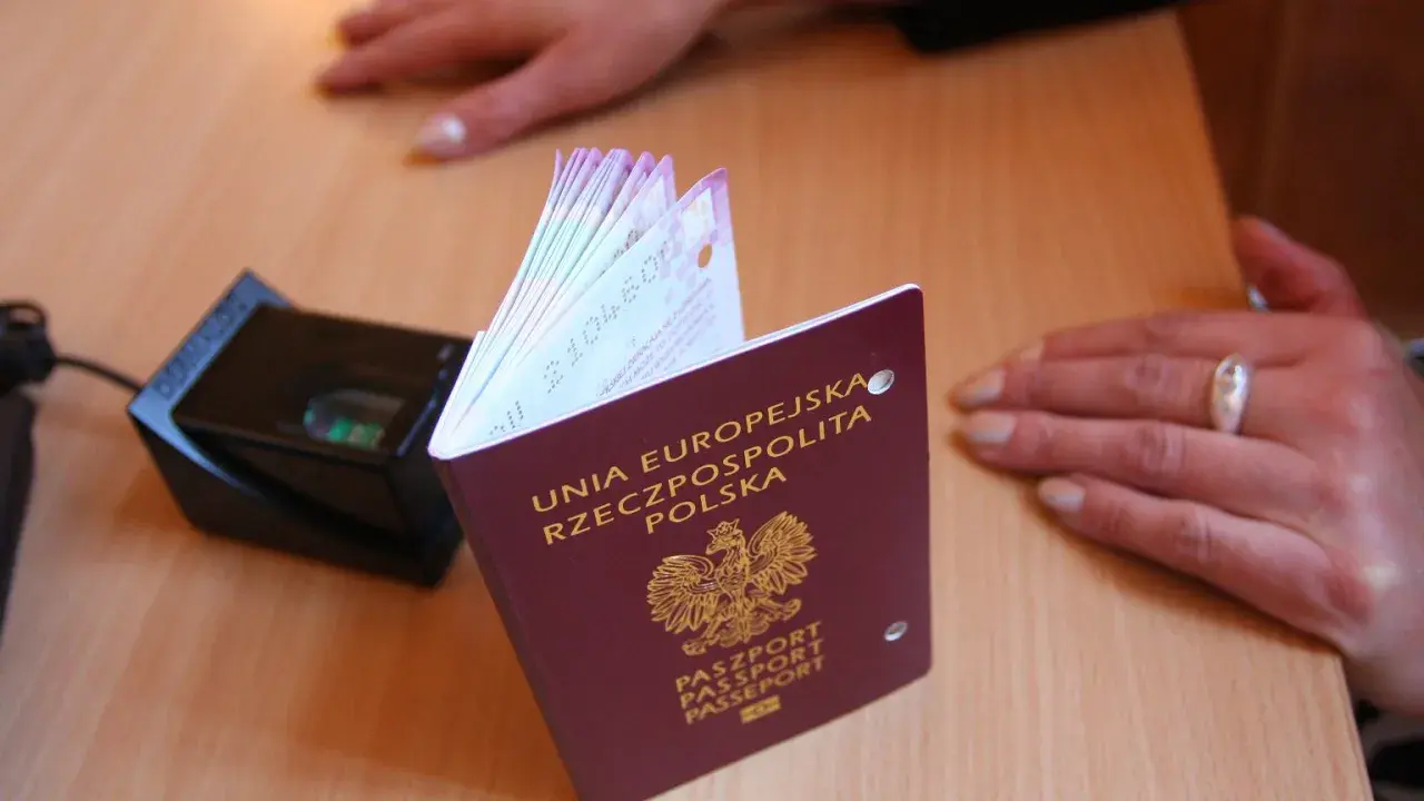 Polski paszport obok skanera linii papilarnych. Dokument z godłem Polski, gotowy do podróży.