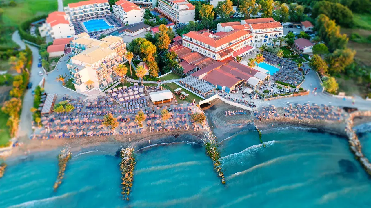 Widok z lotu ptaka na hotel z basenem i plażą pełną leżaków i parasoli. Idealne miejsce na wakacje, jak z marzeń, niczym z katalogu Itaka.