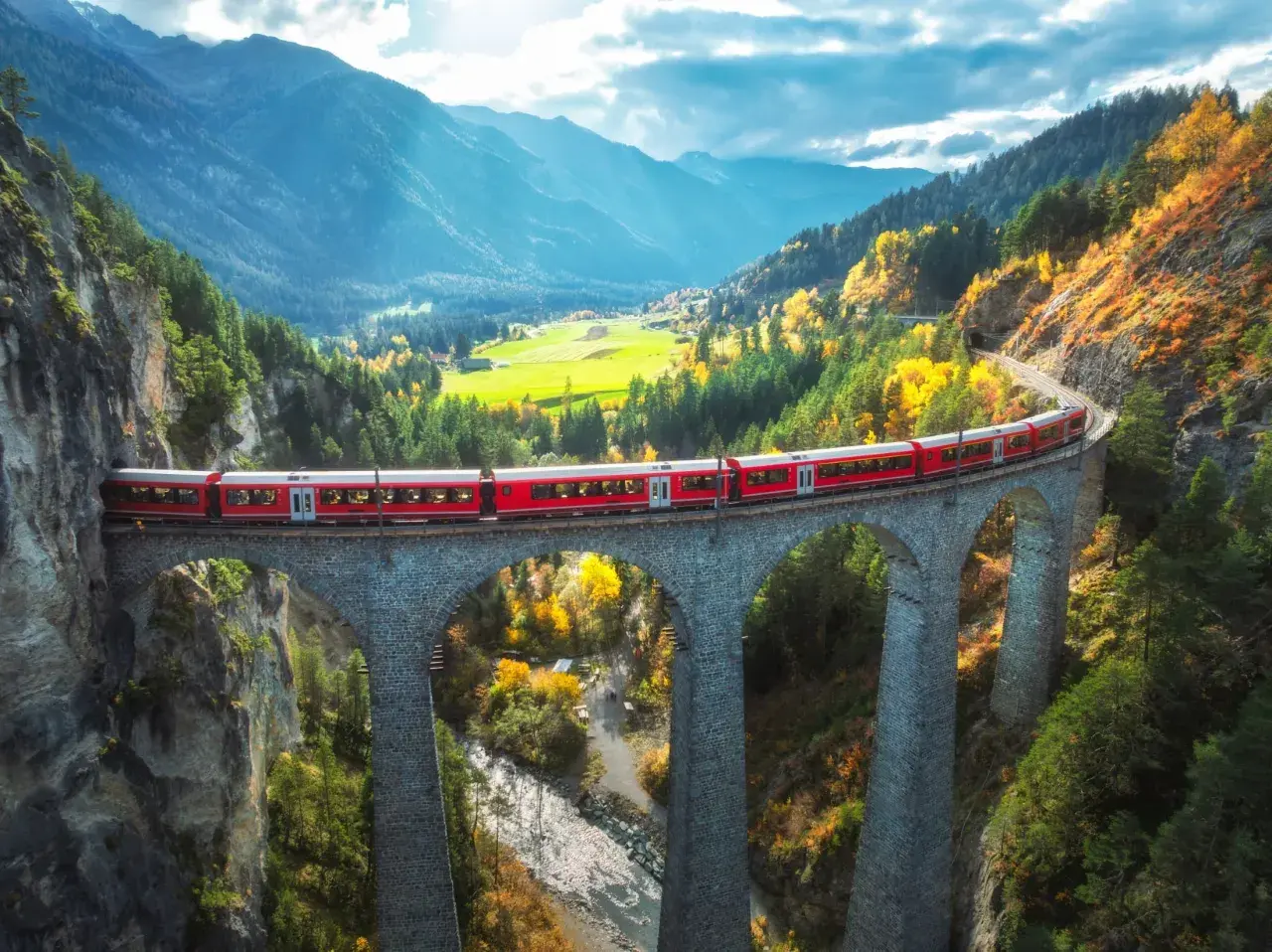 Czerwony pociąg Bernina Express przemierza malowniczy alpejski krajobraz jesienią. Sprawdź bernina express cena i zaplanuj podróż!