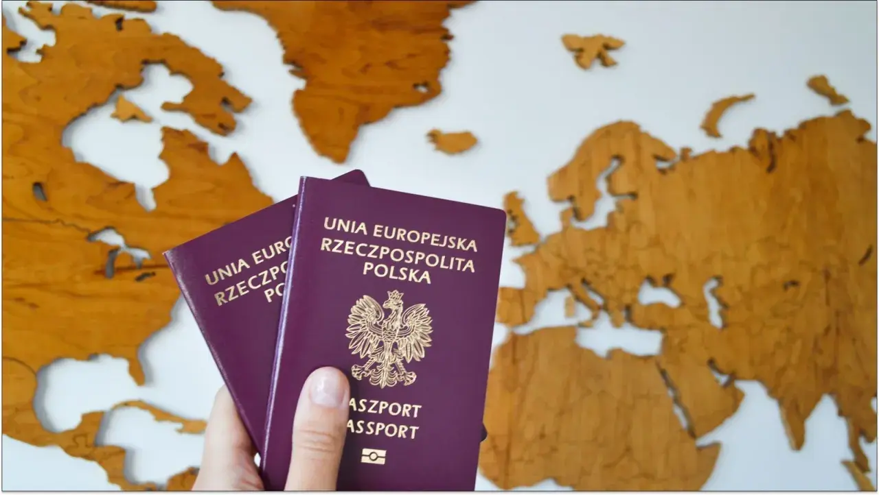 Dwa polskie paszporty na tle drewnianej mapy świata. Zastanawiasz się, ile kosztuje paszport tymczasowy?