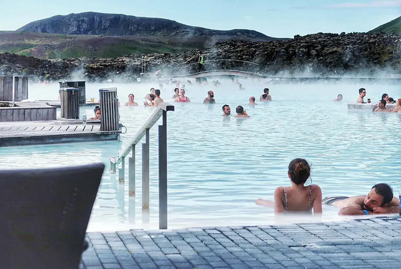 Błękitna laguna Islandia: ludzie relaksują się w geotermalnych wodach, otoczeni parą i surowym krajobrazem.