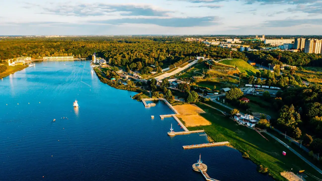 Malownicze jeziora w Polsce na wakacje: rozległy akwen, plaża, molo i zielone tereny rekreacyjne.