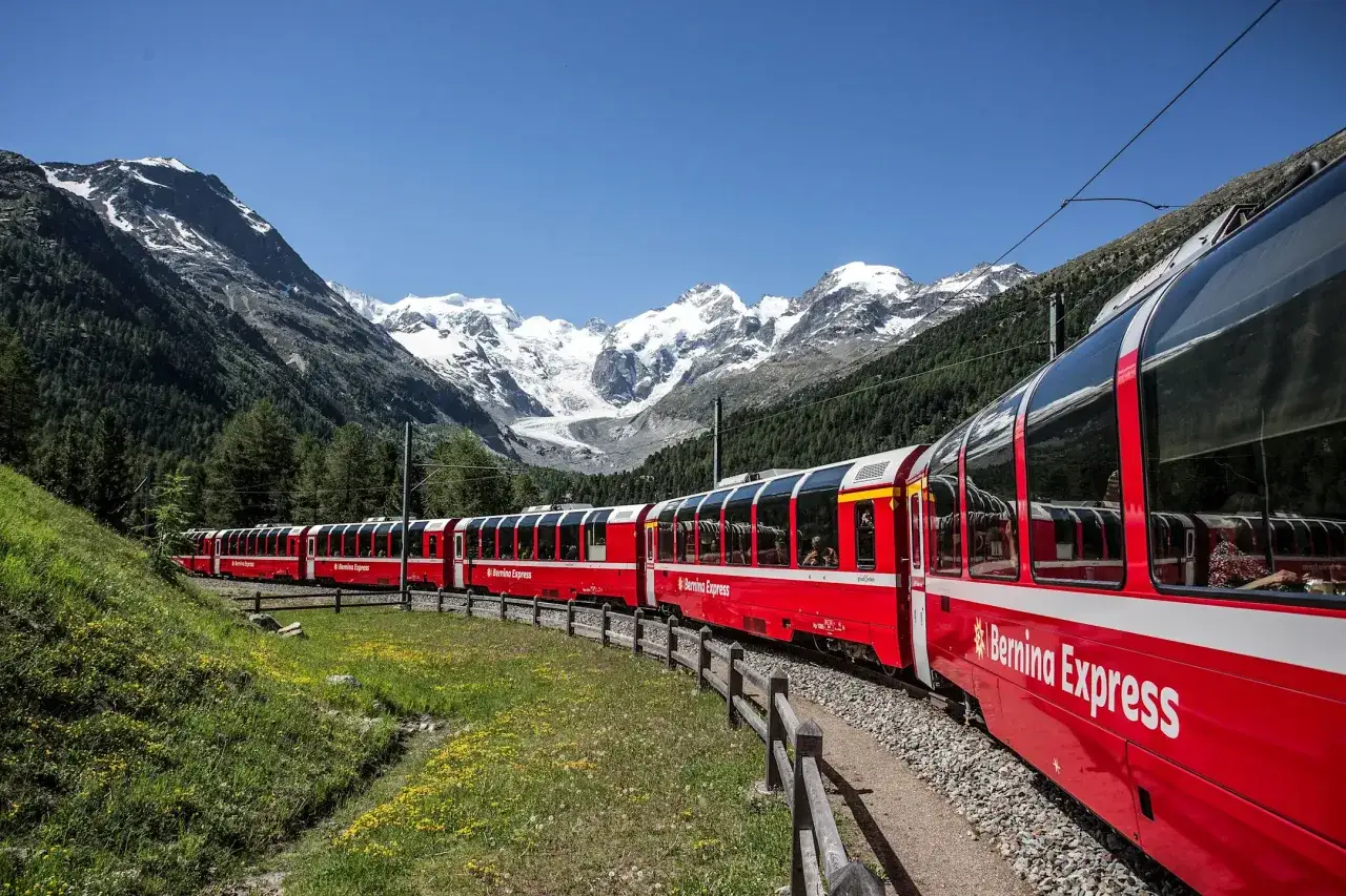 Czerwony pociąg Bernina Express wjeżdża na malowniczy górski zakręt. Sprawdź bernina express cena i zaplanuj podróż!