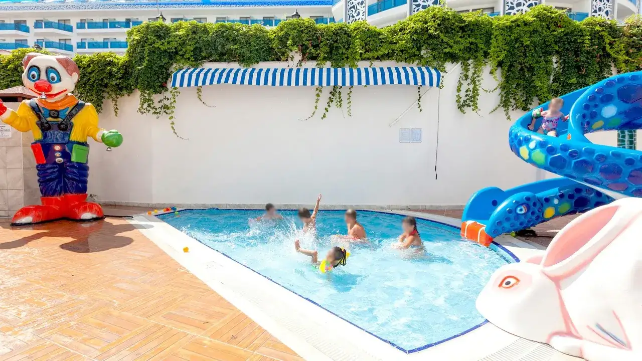 Dzieci bawią się w basenie hotelu Narsia Resort, obok zjeżdżalni i figury klauna.